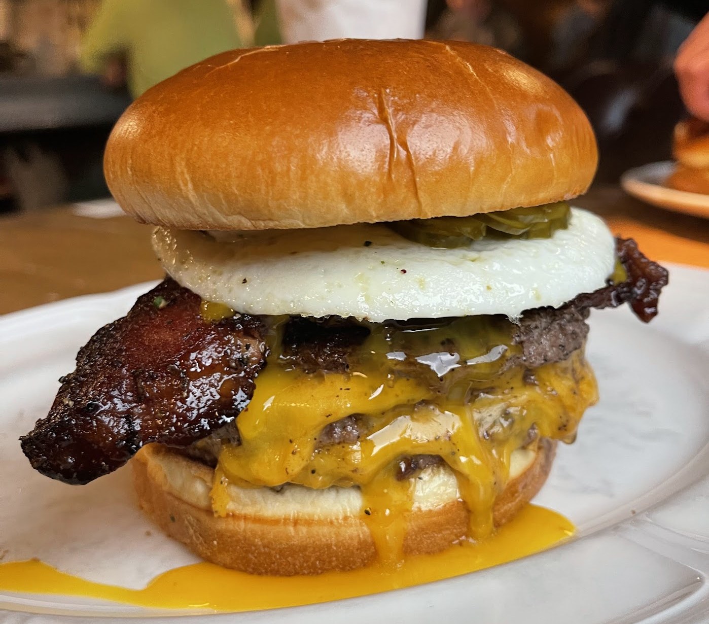 Au Cheval's bacon, egg, and cheese burger, dripping with melted cheddar, on a marble plate